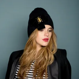 Czarna czapka premium z kokardą i złotym robakiem.