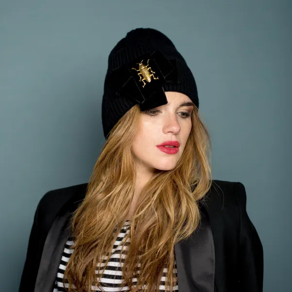 Czarna czapka premium z kokardą i złotym robakiem.