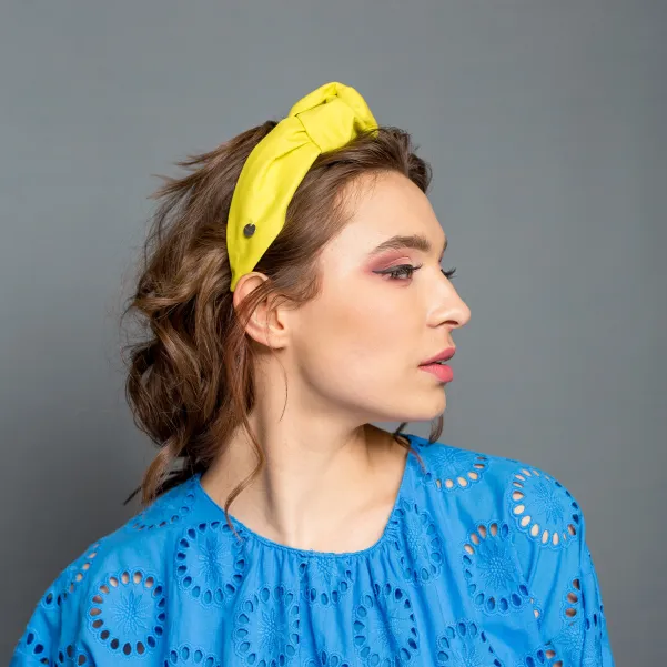 Sztywna opaska do włosów w żółtym kolorze.