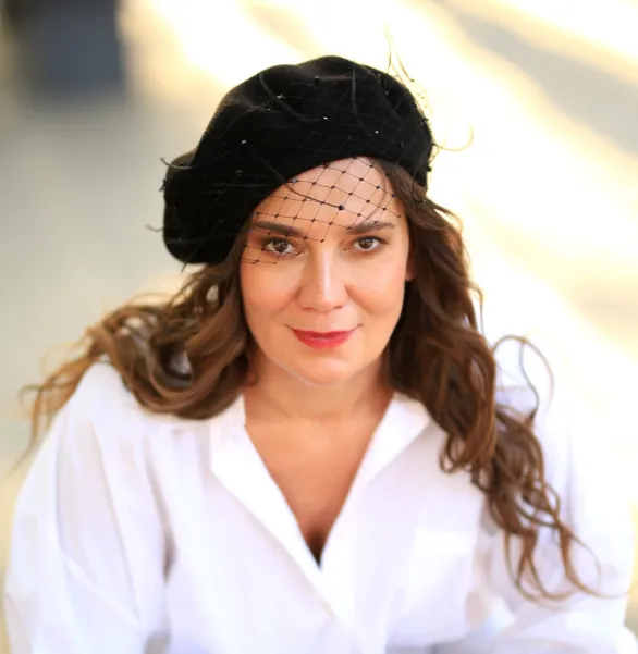 Czarny beret z woalką, piórkami i kryształkami.