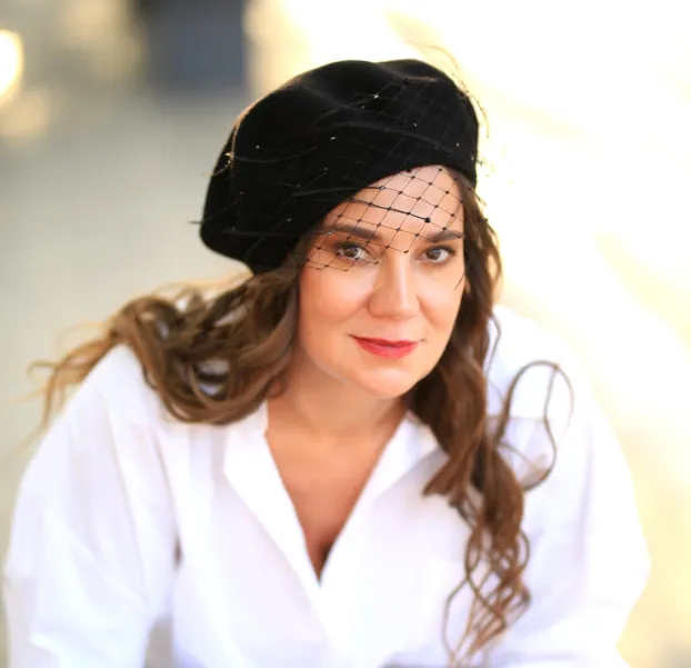 Czarny beret z woalką, piórkami i kryształkami.