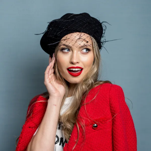 Czarny beret z woalką, piórkami i kryształkami.