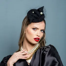 Czarny kapelusik z perłami i woalką.