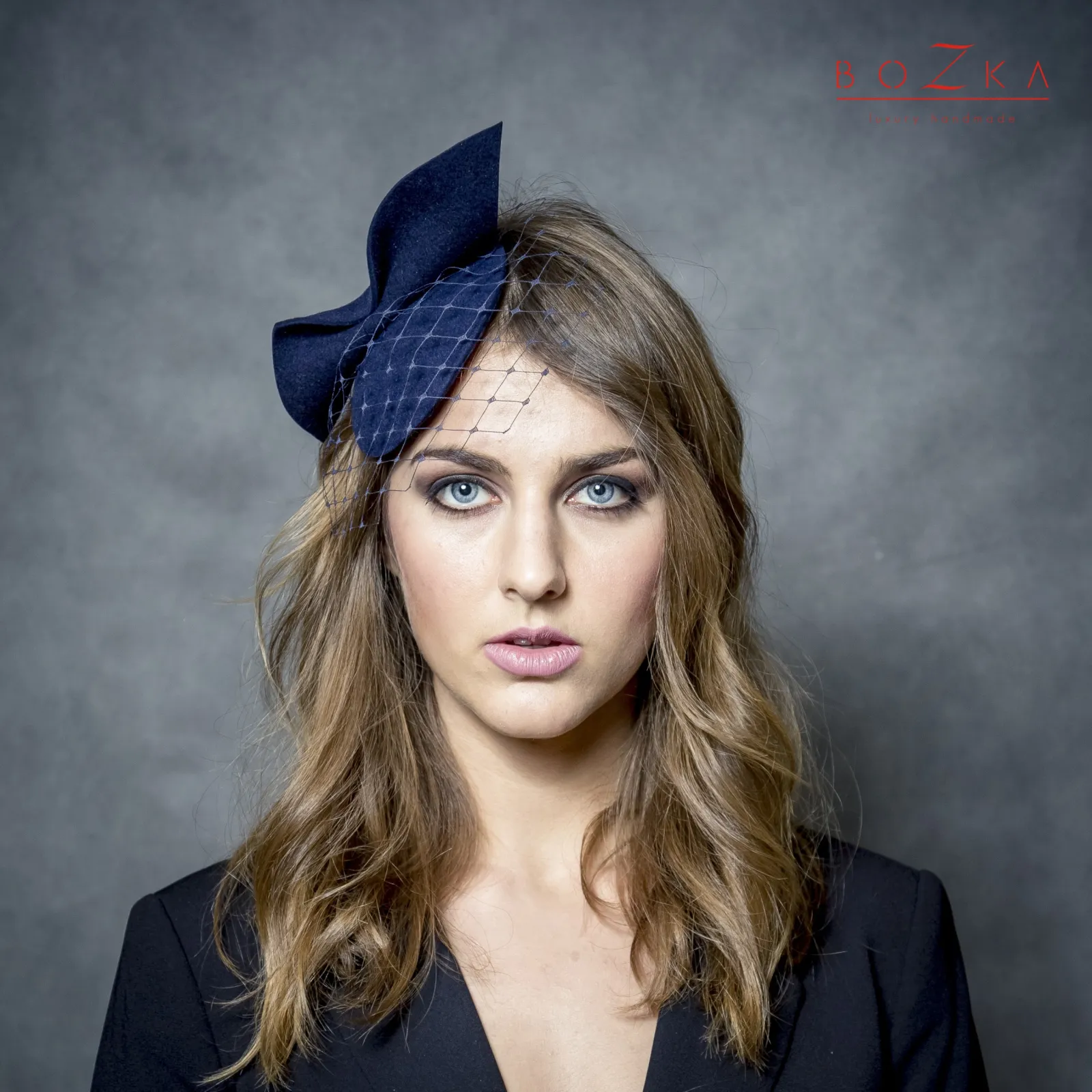 Granatowy filcowy nowoczesny stroik na głowę z kokardą i z woalką.