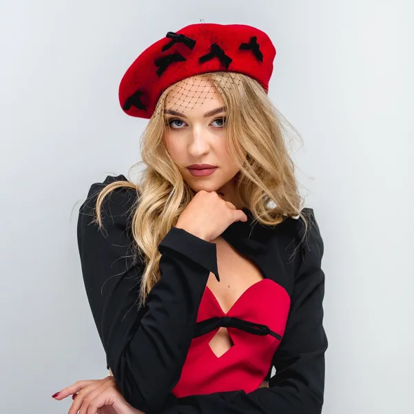 Czerwony beret ozdobny z  kokardkami i z woalką.