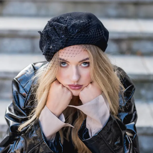 Czarny beret damski z woalką i ozdobą z tweedu.