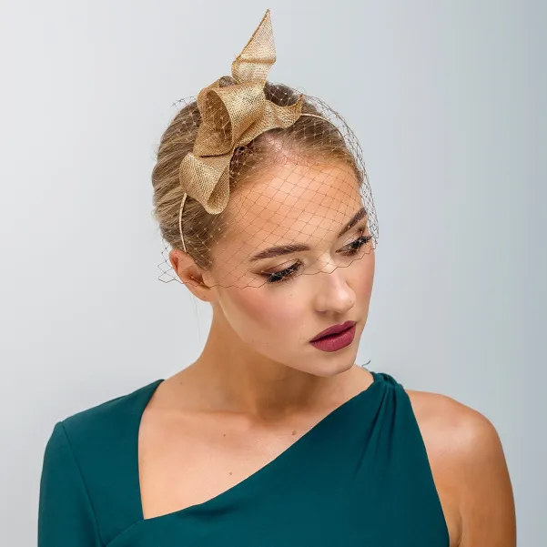 Złoty fascynator falująca kokarda z woalką.