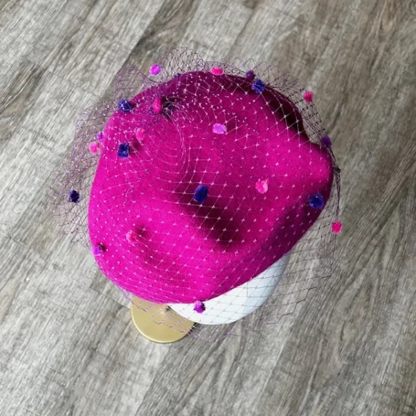 Różowy beret z nakrapianą woalką.