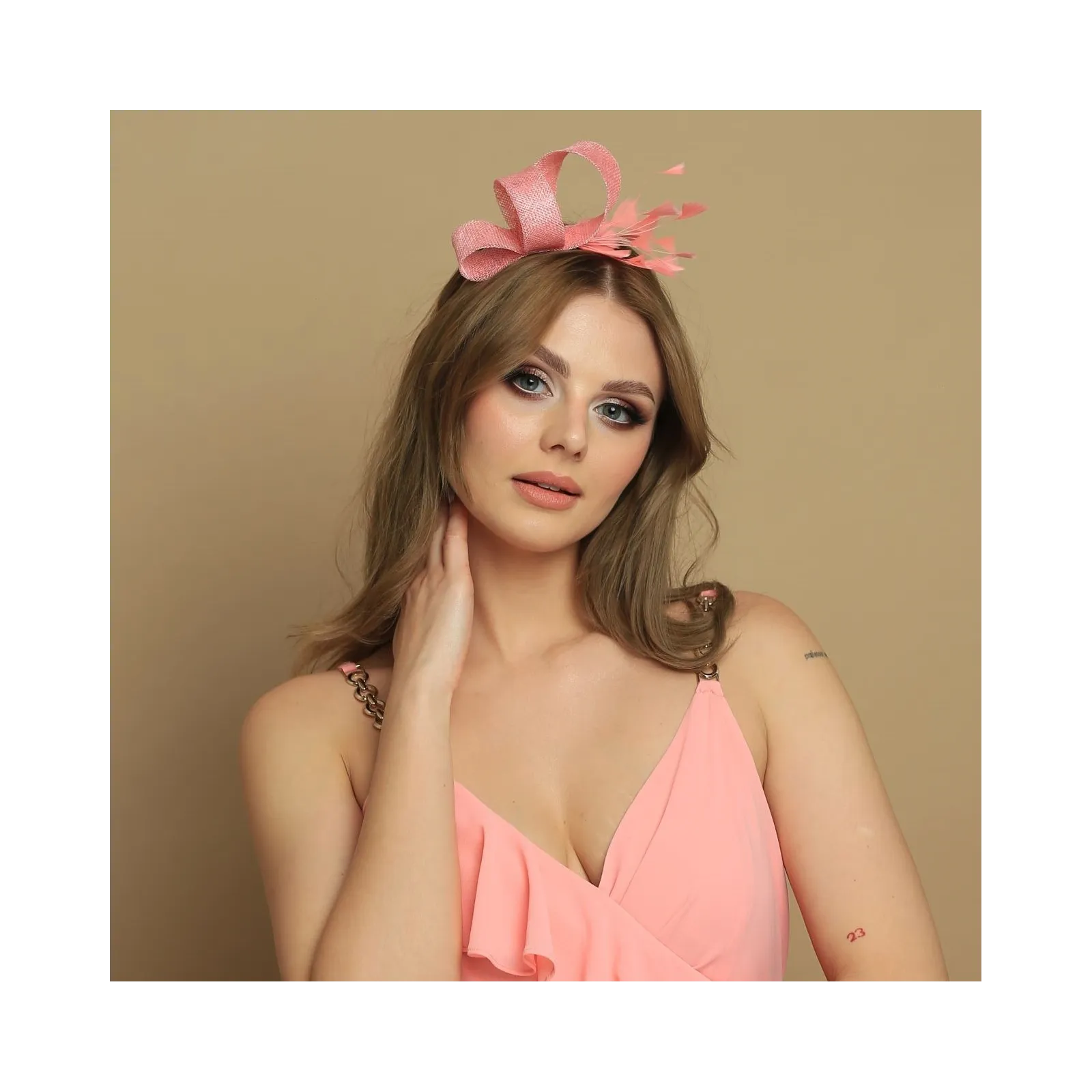 Brzoskwiniowy fascynator z delikatnymi piórami.