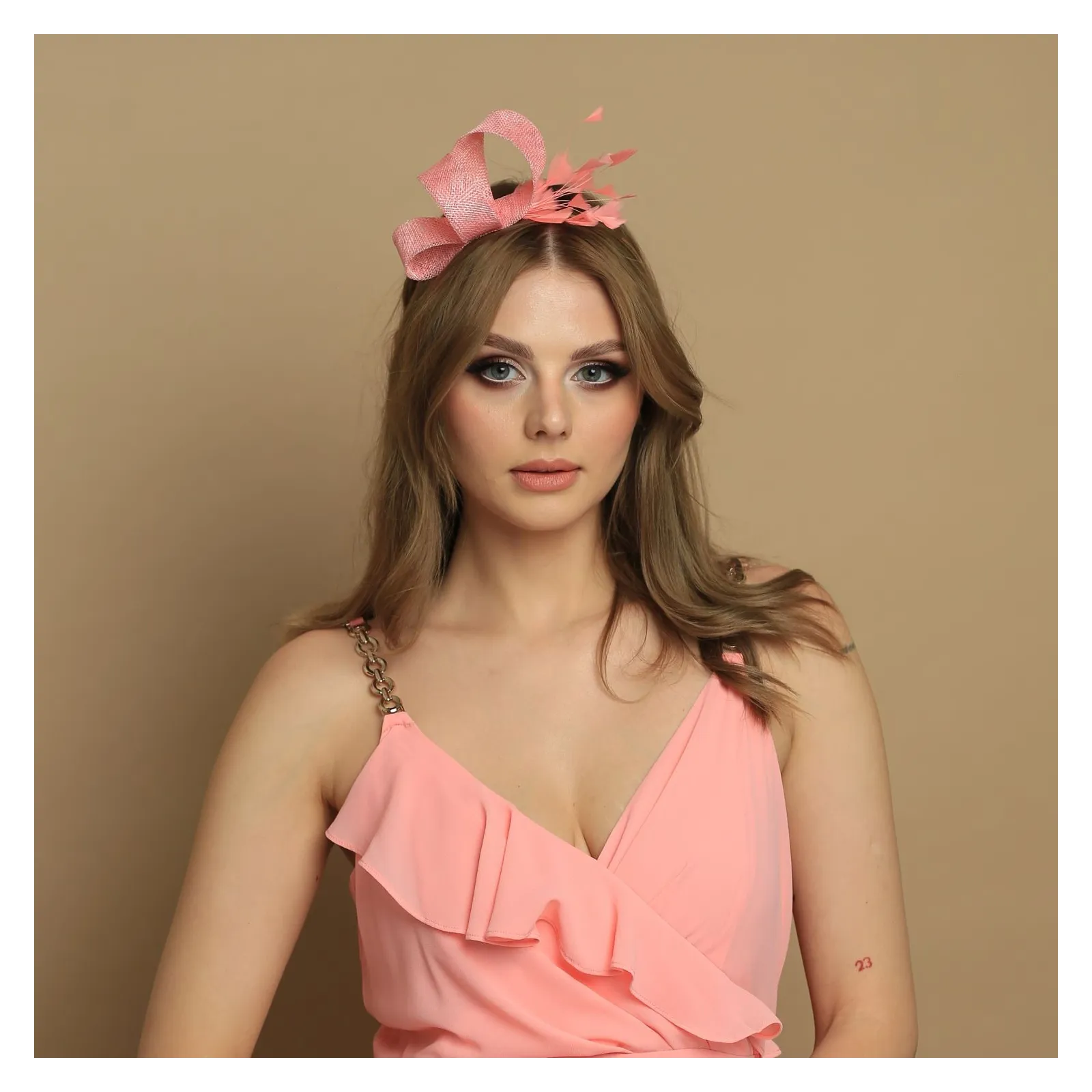 Brzoskwiniowy fascynator z delikatnymi piórami.