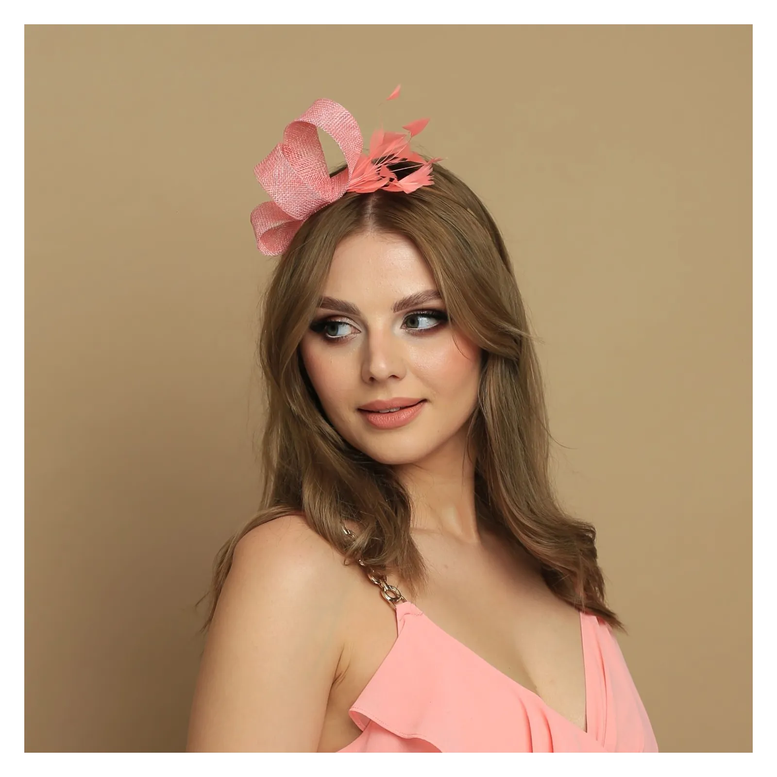 Brzoskwiniowy fascynator z delikatnymi piórami.