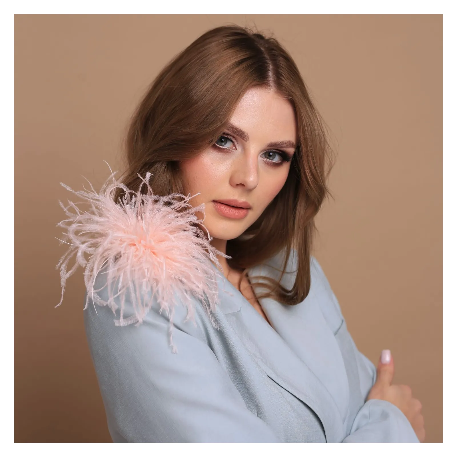 Brzoskwiniowa modna broszka z piórkami.