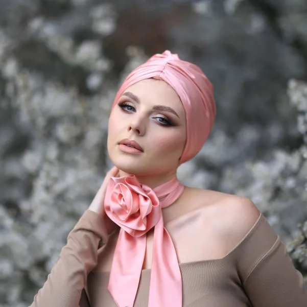 Apaszka twilly z brzoskwiniowym kwiatem na szyję.