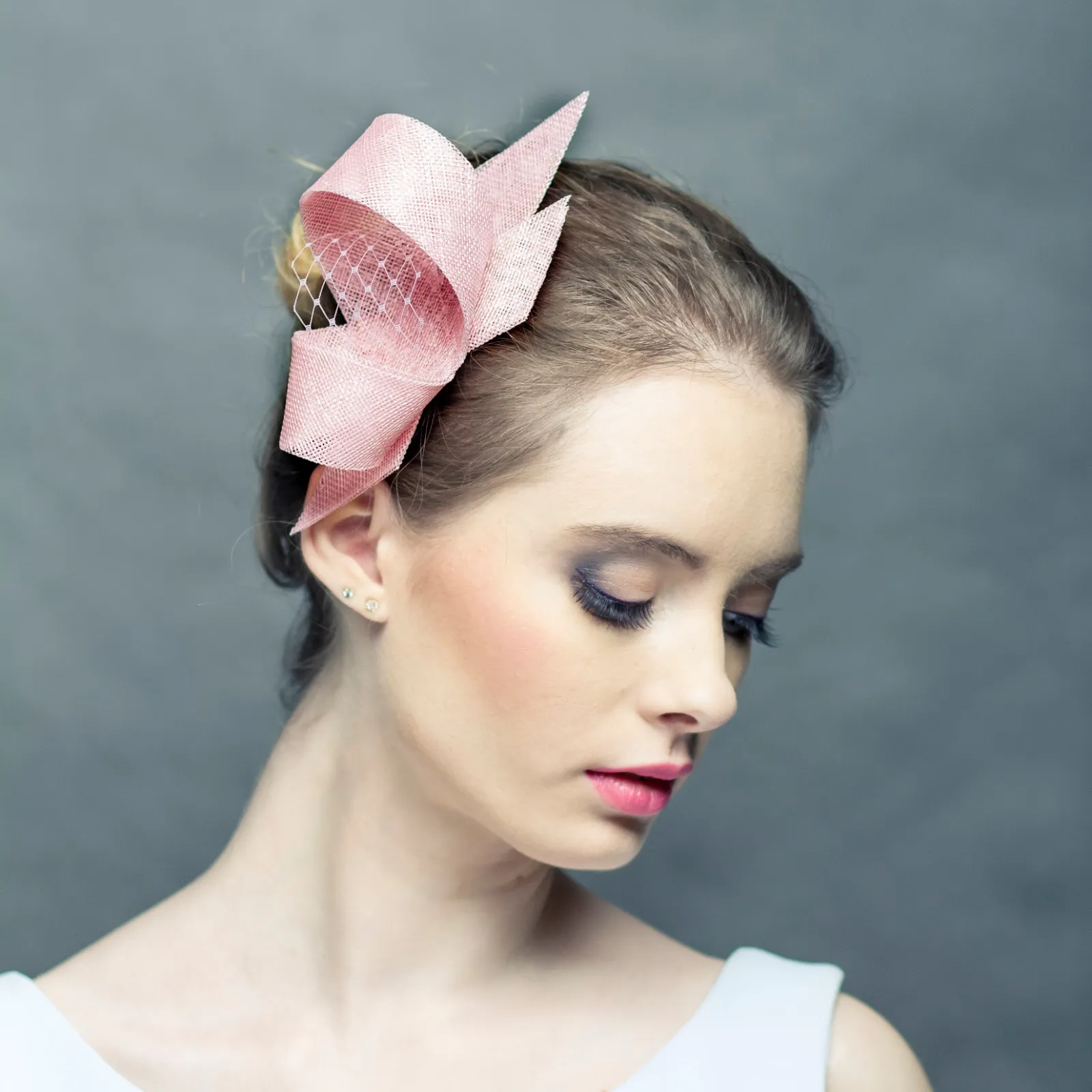 Pudrowy różowy fascynator z woalką.