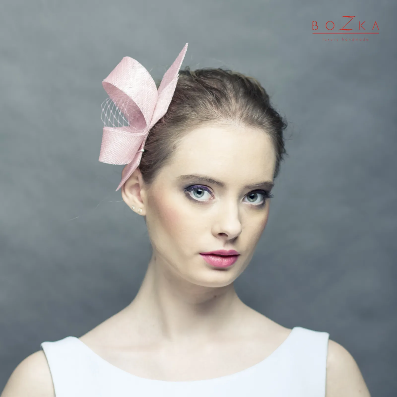 Pudrowy różowy fascynator z woalką.