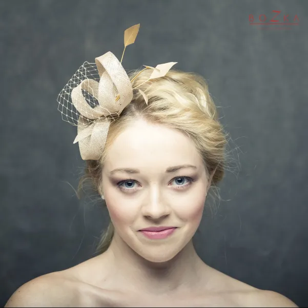 Beżowy fascynator na głowę z piórkami i woalką. Beżowy fascynator na głowę z piórkami i woalką.