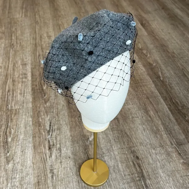 Szary beret z woalką w kropki.