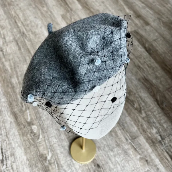 Szary beret z woalką w kropki.