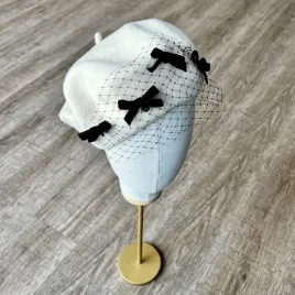 Kremowy beret z woalką i kokardkami.