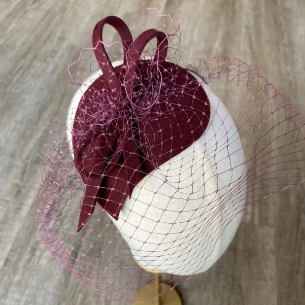 Bordowy toczek na głowę o oryginalnym kształcie z woalką.