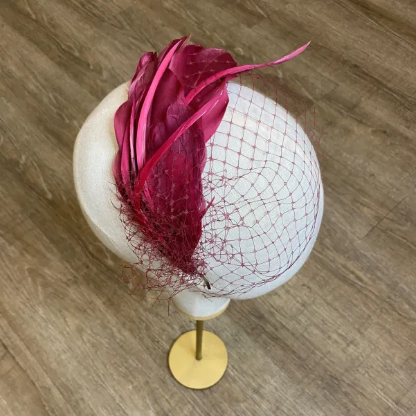 Wiśniowy fascynator z piór z woalką.