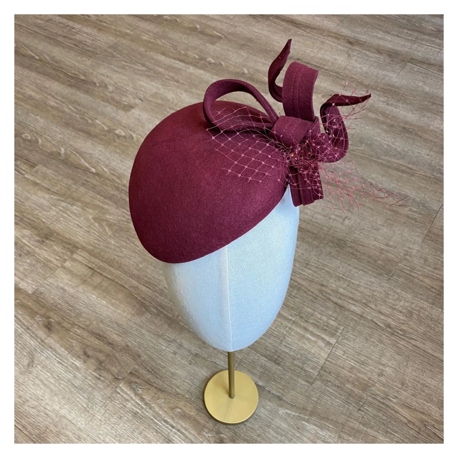 Ozdobne nakrycie głowy- mały burgundowy kapelusz.