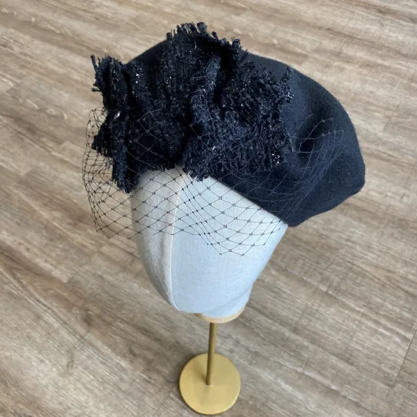 Czarny beret damski z woalką i ozdobą z tweedu.