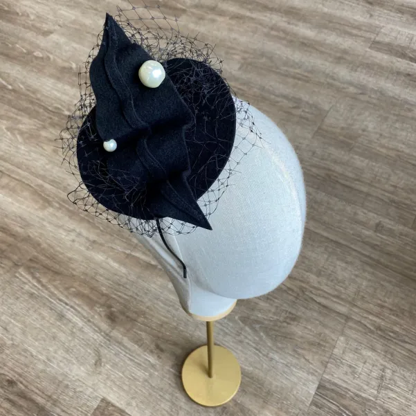 Czarny kapelusik z perłami i woalką.