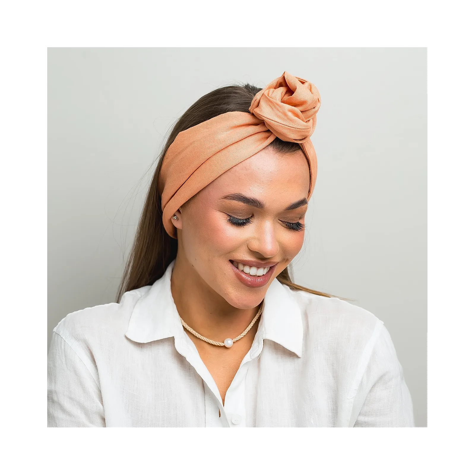 Lniana opaska twistband w kolorze brzoskwiniowym.