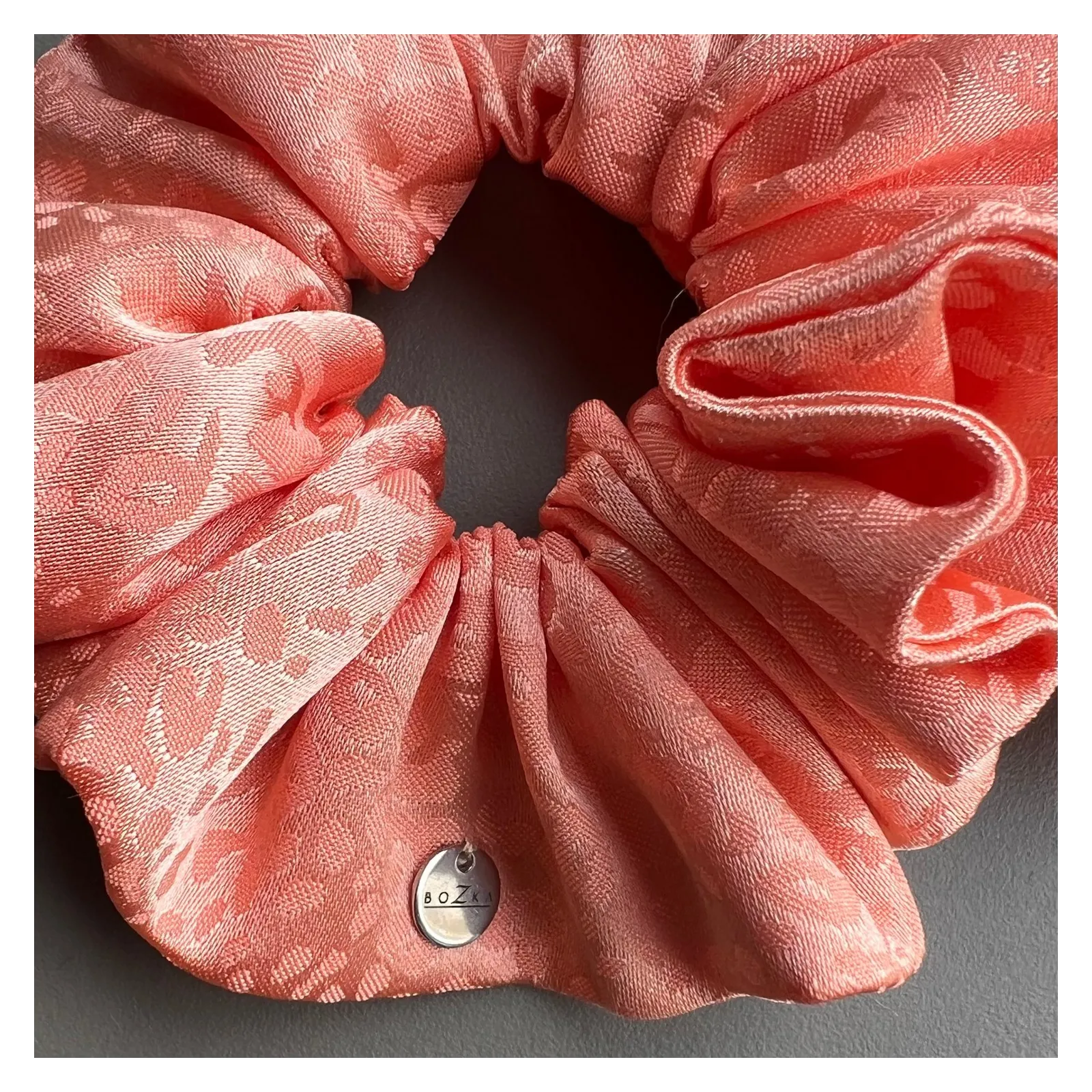 Duża jedwabista gumka do włosów brzoskwiniowa.