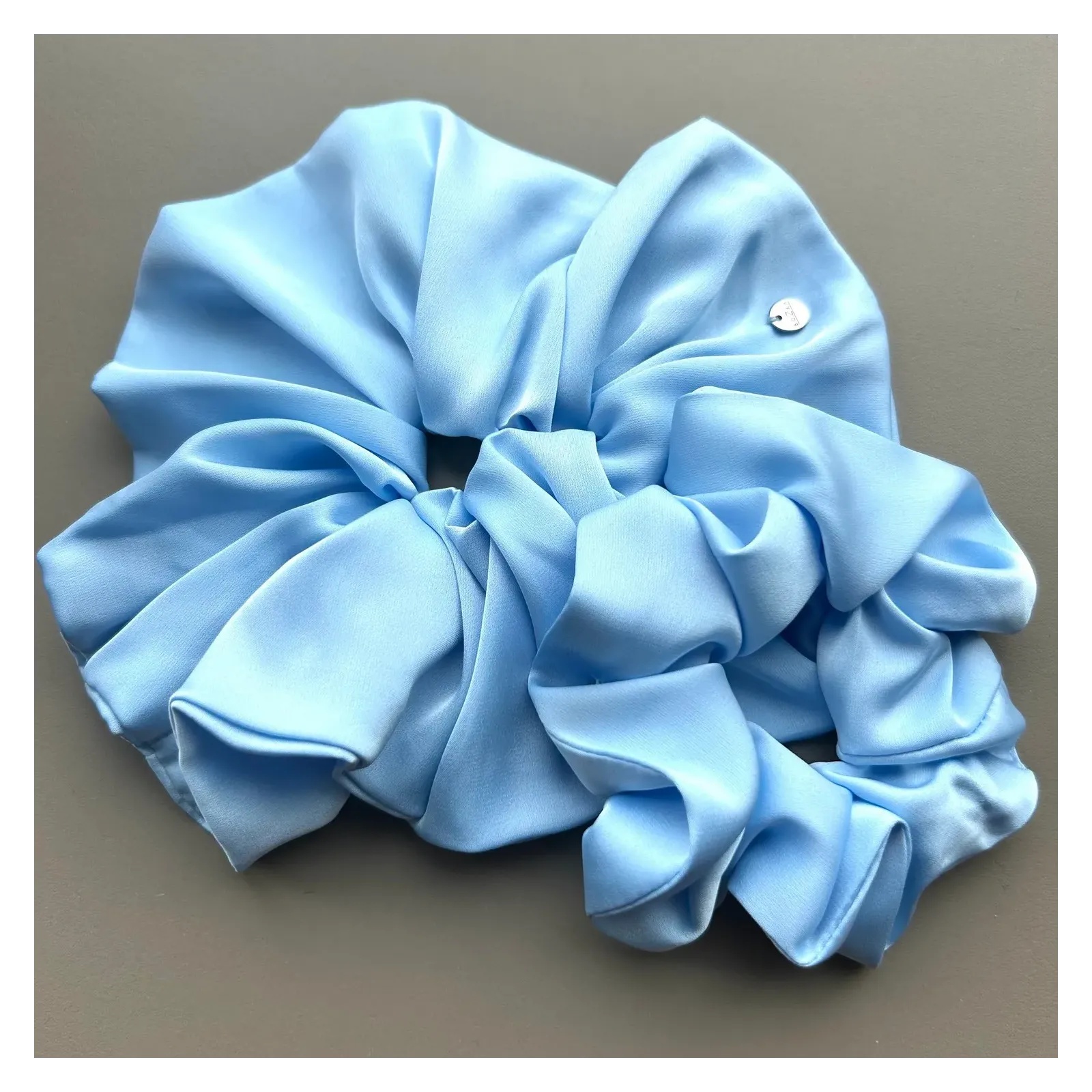 Duża, jedwabista gumka scrunchie w odcieniu błękitu.