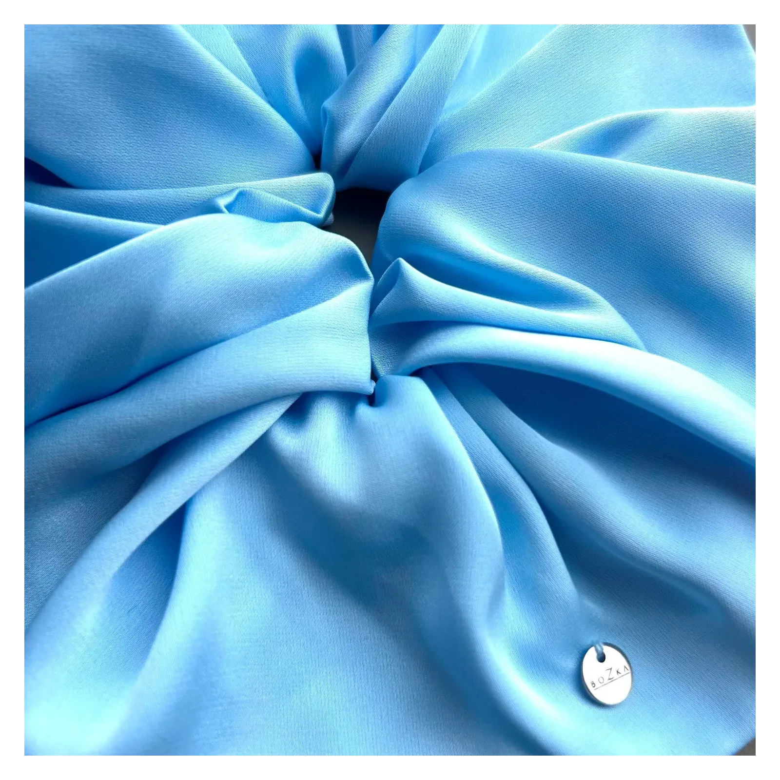 Mała, jedwabista gumka w odcieniu błękitu.