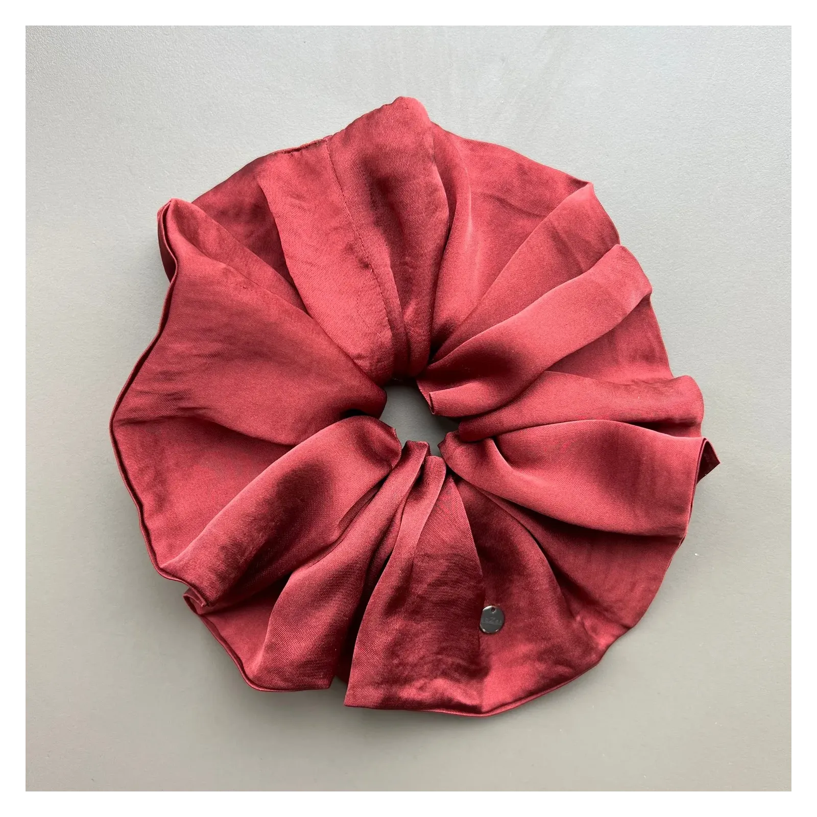 Duża, jedwabista gumka scrunchie w odcieniu bordo.