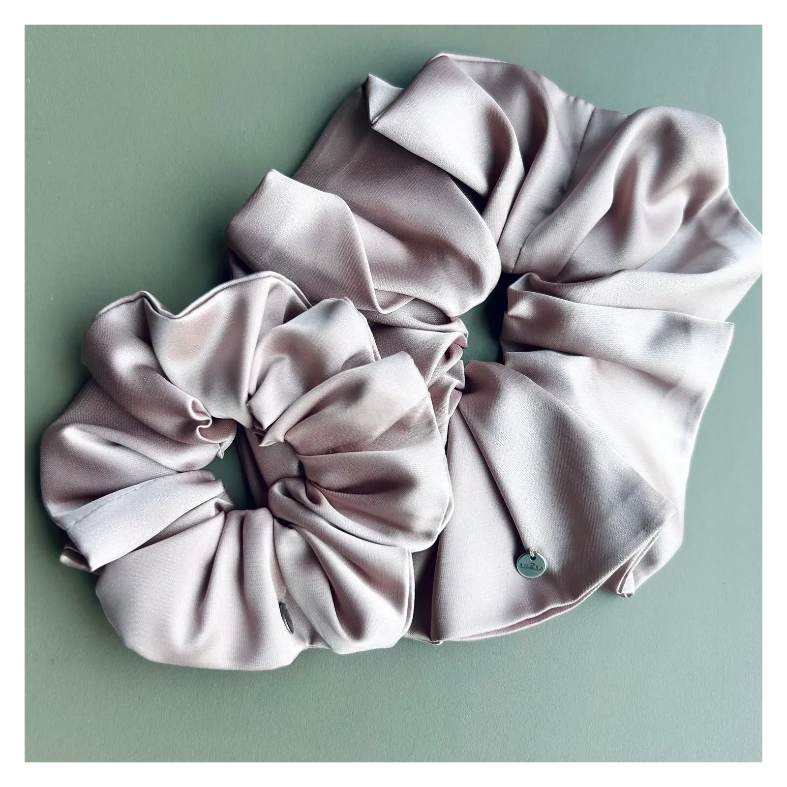 Duża, jedwabista gumka scrunchie w odcieniu pudrowy róż.