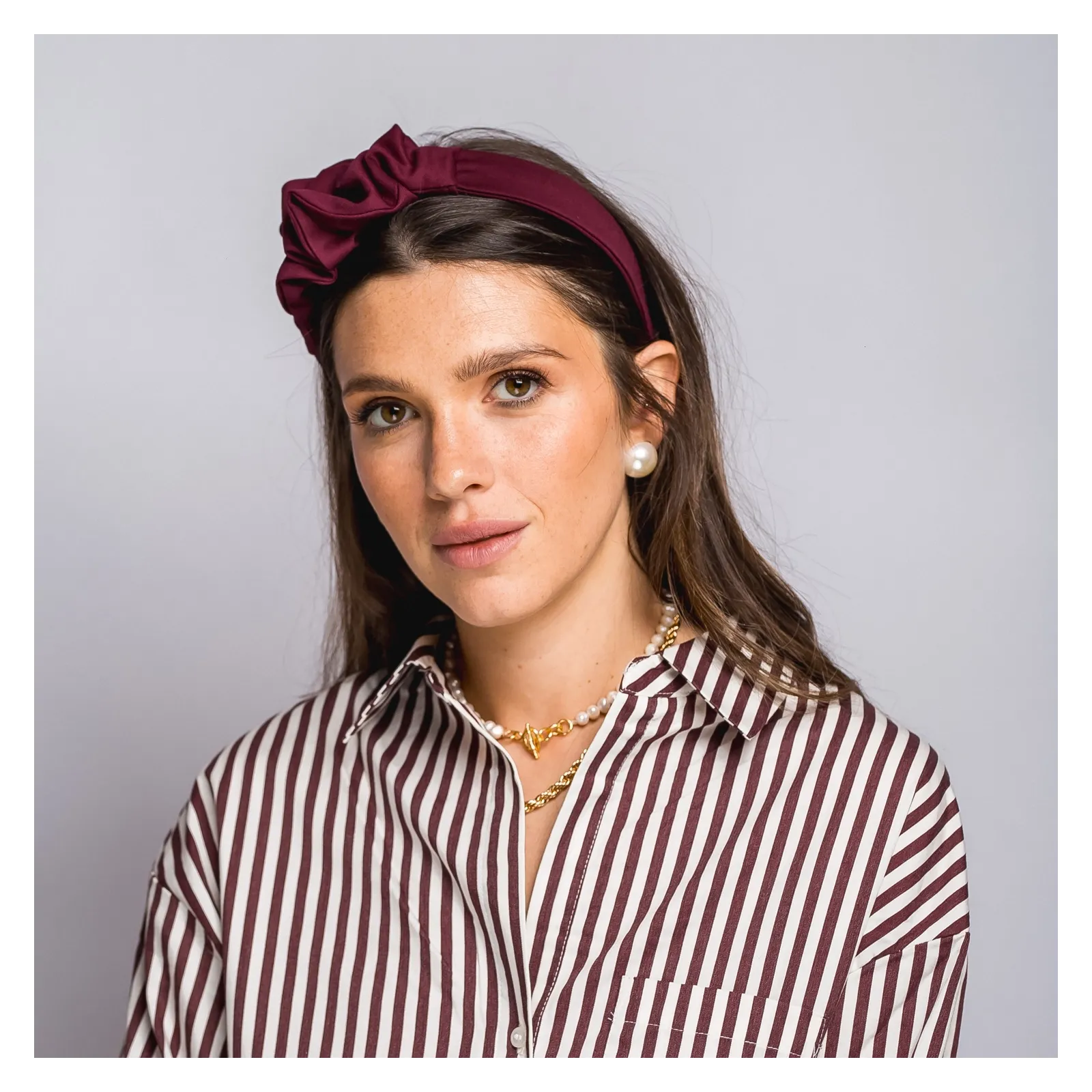 Bordowa opaska do włosów z niewielką ozdobą.