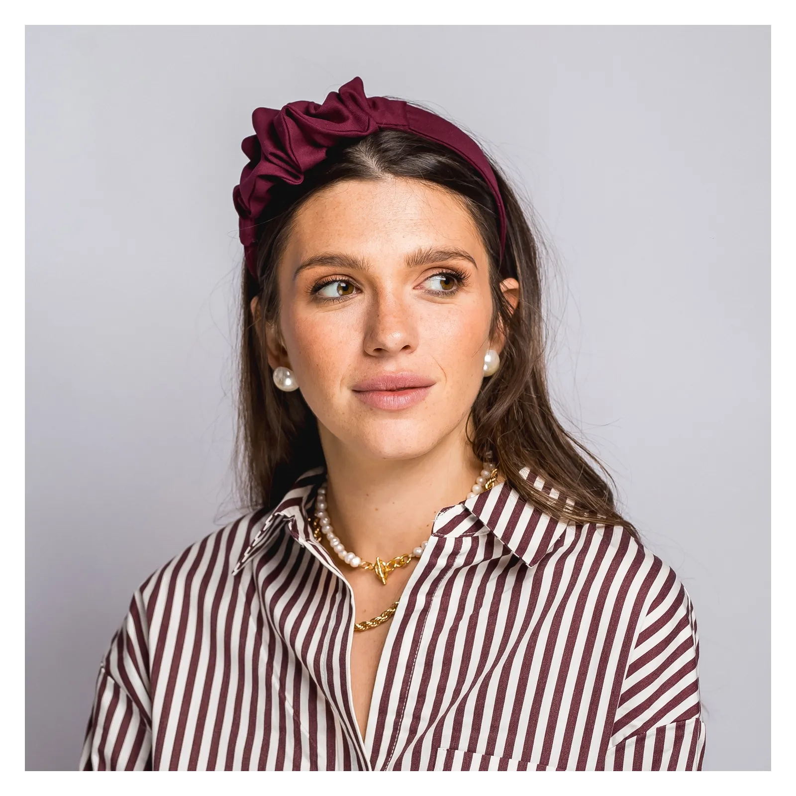 Bordowa opaska do włosów z niewielką ozdobą.