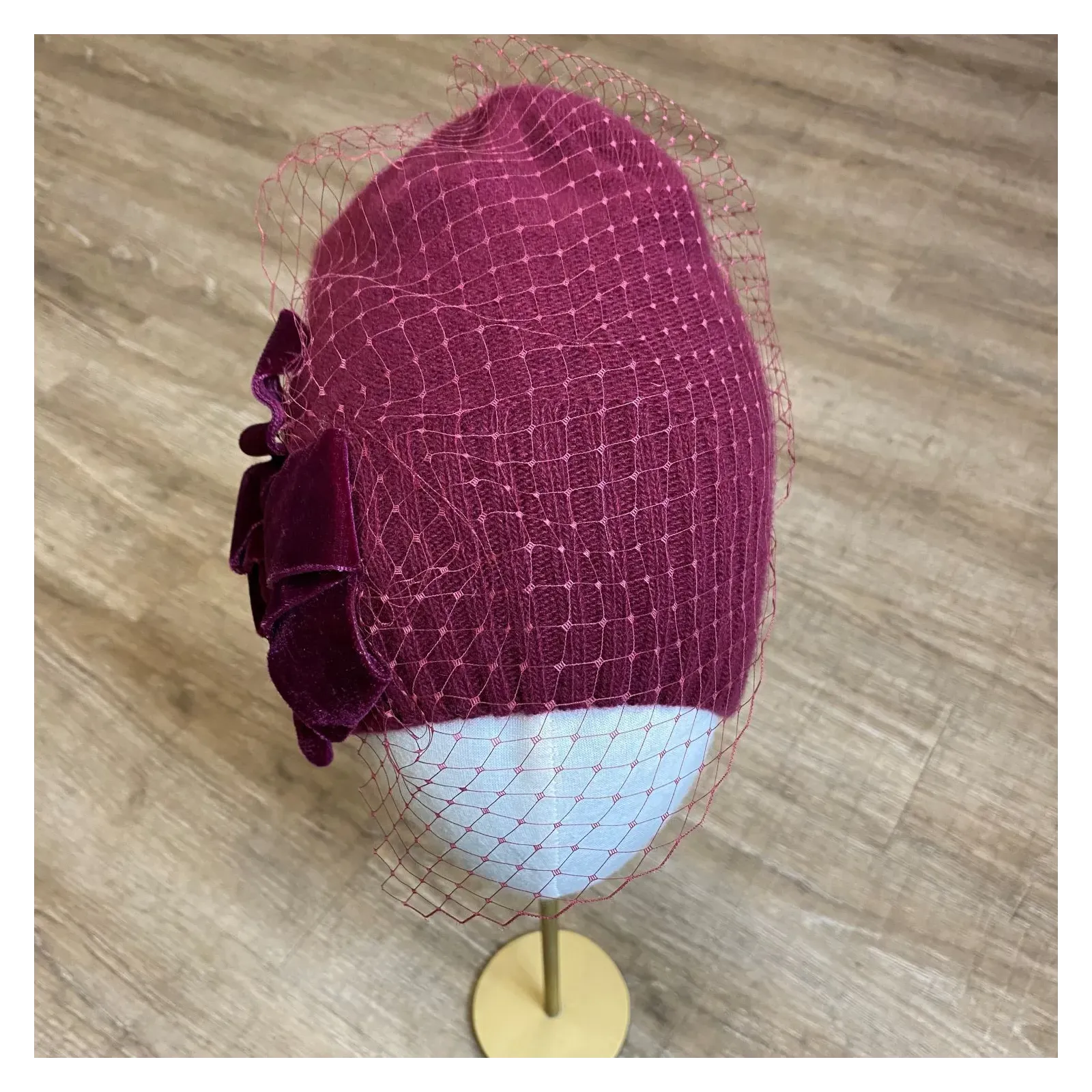 Burgundowa zdobiona czapka wełniana z woalką i kokardą.