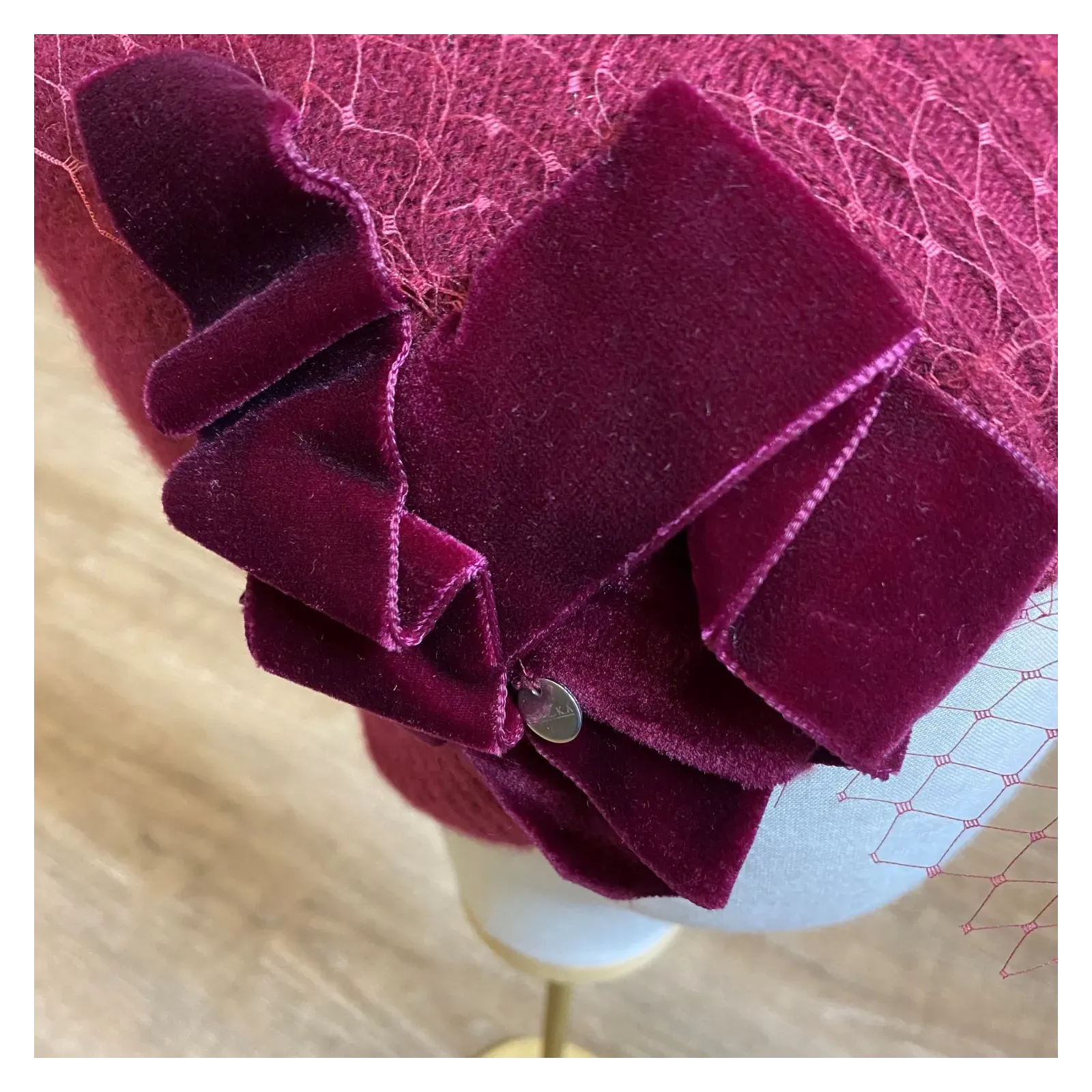 Burgundowa zdobiona czapka wełniana z woalką i kokardą.