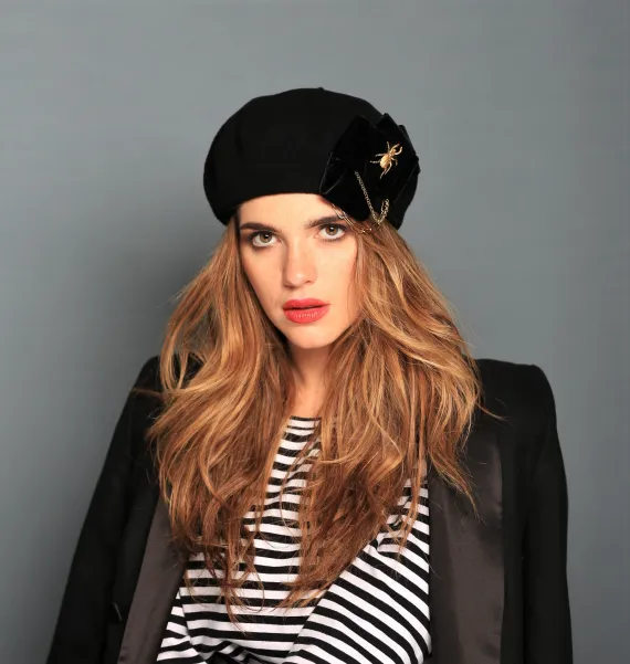 Stylowy beret z kokardą, łańcuchami i złotą ozdobą.